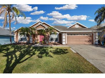 Charming single-story home with a well-manicured lawn, palm trees, and a two-car garage at 1940 Southern Dunes Blvd, Haines City, FL 33844