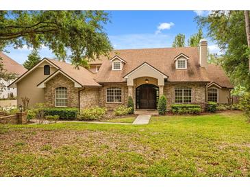 Charming brick home features a well-manicured lawn, mature trees, and a welcoming front entrance at 8800 Torey Pines Ter, Orlando, FL 32819