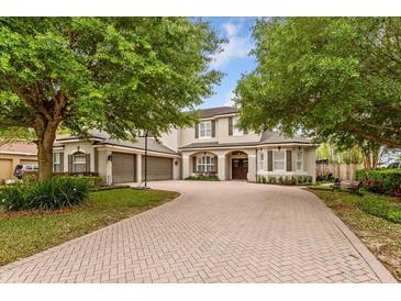 Charming home featuring a brick driveway, three-car garage, and manicured landscaping at 9880 Montclair Cir, Apopka, FL 32703