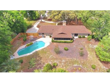 Aerial view of the backyard featuring a sparkling pool, wood fence, lush landscaping, and home with screened in lanai at 1212 Foxfire Dr, Apopka, FL 32712