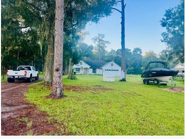 Charming single-story home with a well-maintained lawn, boat, and truck in a serene, wooded setting at 1908 W Socrum Loop Rd, Lakeland, FL 33810
