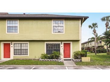 Inviting townhome showcasing a vibrant red door and lush landscaping at 3251 Oak Lake Pl # 135, Winter Park, FL 32792