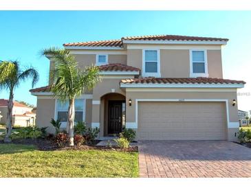 Charming two-story home featuring a red tile roof, two-car garage and well manicured lawn with tropical landscaping at 4420 Shiva Loop, Kissimmee, FL 34746