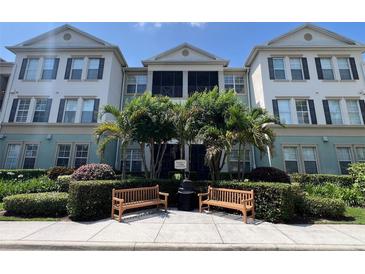 Well-maintained building featuring lush landscaping, benches, and a screened-in porch on the second level at 11446 Jasper Kay Terrace # 202, Windermere, FL 34786