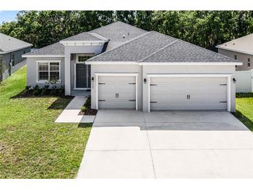 Charming home with a manicured lawn, gray stucco exterior, and a spacious two-car garage at 113 St Thomas Dr, Mulberry, FL 33860
