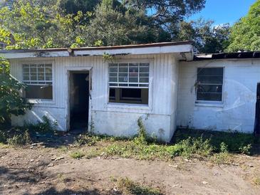 Run-down white home featuring missing panes in the windows and an overgrown yard, ripe for renovation at 1630 S Rio Grande Ave, Orlando, FL 32805