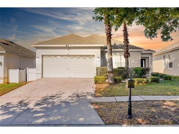 Charming single-story home with a two-car garage, well-manicured lawn, and a brick-paved driveway at 217 Herring St, Davenport, FL 33897