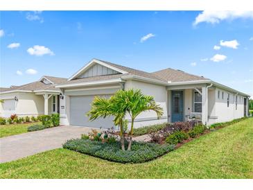 Charming one-story home featuring a manicured lawn, lush garden, and a welcoming blue front door at 2457 Cliff Way, St Cloud, FL 34771