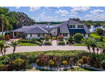 Charming two-story home with beautiful landscaping, an inviting circular driveway, and a waterside view at 4301 Down Point Ln, Windermere, FL 34786