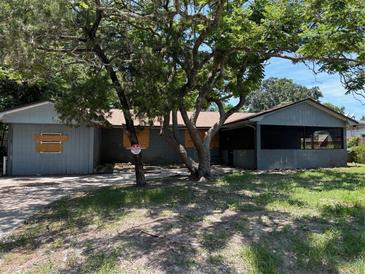 Exterior view of a single-story home with boarded windows and a screened-in porch at 4302 Seybold Ave, Orlando, FL 32808