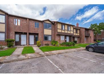 Brick townhome featuring a lush lawn, manicured landscaping, and ample parking at 5060 Downing St # 6, Orlando, FL 32839