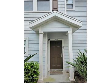 Inviting front door entrance with a peaked roof, light blue siding, and lush landscaping at 5354 Diplomat Ct # 105, Kissimmee, FL 34746