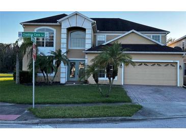 Inviting two-story home featuring a manicured lawn, mature palm trees, and a convenient two-car garage at 5803 Cheshire Cove Ter, Orlando, FL 32829