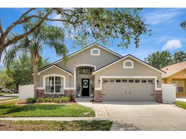 Charming single-story home with a well-manicured lawn and neutral gray and stone exterior at 11209 Taeda Dr, Orlando, FL 32832