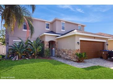 Charming two-story home featuring a stone-accented entrance and a well-maintained lawn at 1423 Marsh Meadow Ln, Davenport, FL 33896
