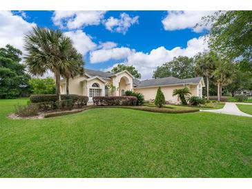 Charming single-story home with a manicured lawn, tasteful landscaping, and mature palm trees enhancing the curb appeal at 1709 Iverness Ct, Longwood, FL 32779