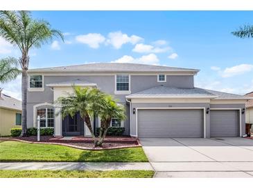 Charming two-story home featuring a three-car garage, well manicured lawn and mature palm trees at 1712 Boat Launch Rd, Kissimmee, FL 34746