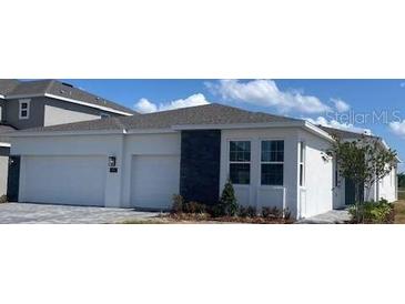 Charming single-story home featuring a clean white facade, stone accents, and a spacious three-car garage at 2152 Rock Maple Bnd, Kissimmee, FL 34746