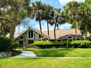 Charming home with lush landscaping, stone accents, and tall palm trees creating a tropical feel at 2155 Palm View Dr, Apopka, FL 32712
