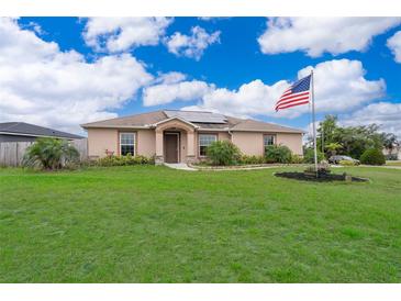 Charming single-story home with a lush green lawn, front garden, and flagpole with an American flag at 2602 Adelia Blvd, Deltona, FL 32725
