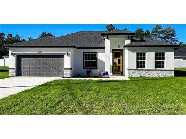 Charming single-story home featuring a gray garage door, stone accents, and a welcoming front yard at 4634 Sw 170Th Road, Ocala, FL 34473