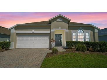 Charming single-story home featuring a well-manicured lawn, brick driveway, and a two-car garage at 838 Kildrummy Dr, Davenport, FL 33896