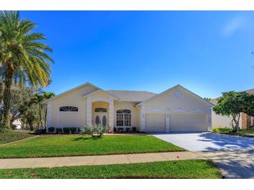 Charming one-story home featuring a two-car garage, well-manicured lawn and palm trees at 1701 Knotting Hill Dr, Orlando, FL 32835
