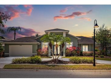 Charming home with lush landscaping, palm trees, and a well-maintained lawn at sunset at 1723 Lee Janzen Dr, Kissimmee, FL 34744