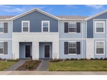 Charming two-story townhome with blue siding, black shutters, and well-maintained landscaping at 3838 Lana Ave, Davenport, FL 33897