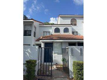 Charming townhouse exterior with black gated entrance, terracotta tile roof, and well-maintained landscaping at 4706 Sutton Ter # 111A2, Orlando, FL 32811