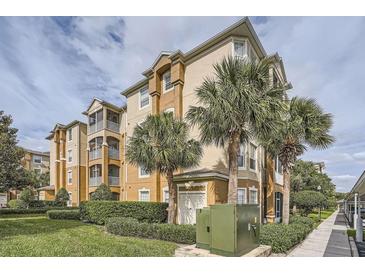Exterior shot of the tan three story condo with palm trees and manicured landscaping at 6402 Cava Alta Dr # 107, Orlando, FL 32835