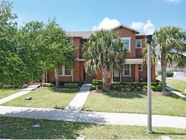 Charming townhome featuring lush landscaping, sidewalk and a beautiful outdoor space with palm trees at 6524 Calamondin Dr, Winter Garden, FL 34787