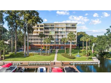 View of multi story condo building with waterfront access, dock, and lush tropical landscaping at 690 Osceola Ave # 502, Winter Park, FL 32789