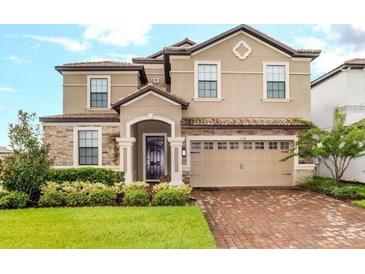 Charming home featuring a two-car garage, manicured lawn, and a stone and stucco exterior at 1518 Rolling Fairway Dr, Davenport, FL 33896