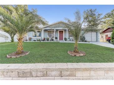 Charming home featuring a well-manicured lawn, vibrant landscaping, and two lovely palm trees at 1905 Lady Ave, Ocoee, FL 34761