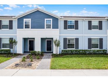 Charming two-story townhome with light blue siding, a well-kept lawn, and appealing front entryway at 301 Jetty Way, Davenport, FL 33897
