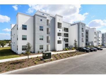 Beautiful three-story condo building with gray and white exterior paint and landscaping at 3191 Paradox Cir # 401, Kissimmee, FL 34746