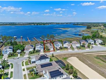 Stunning aerial view of a lakeside property with a well-manicured lawn and beautiful landscaping at 3456 Shallow Cove Ln, Clermont, FL 34711