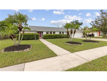 Charming single Gathering home with a well-manicured lawn and mature landscaping, including palm trees at 3994 Irma Shores Dr, Orlando, FL 32817