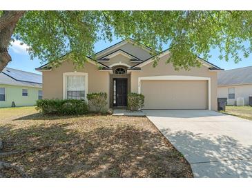 Charming single-story home featuring a two-car garage and a well-maintained front yard with mature trees at 558 Knollwood Dr, Davenport, FL 33837