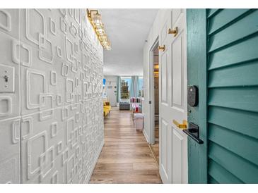 Bright condo hallway featuring stylish wall decor and wood-look floors leading to an inviting living space with ocean views at 800 N Atlantic Ave # 417, Daytona Beach, FL 32118