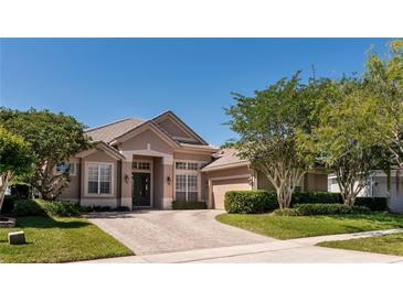 Charming beige single-story home with a tile roof, a brick driveway and mature landscaping at 1027 Algare Loop, Windermere, FL 34786