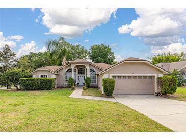 Charming single-story home with a well-manicured lawn, complemented by lush landscaping and an attached two-car garage at 1034 Featherstone Cir, Ocoee, FL 34761