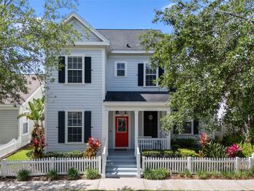 Charming two-story home featuring a red front door, picket fence, and well-manicured landscaping at 109 Grinnell Pl, Celebration, FL 34747