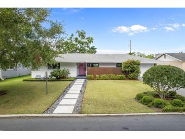 Charming single-story home featuring a modern facade, lush landscaping, and a welcoming pink front door at 113 Tangelo Ct, Maitland, FL 32751