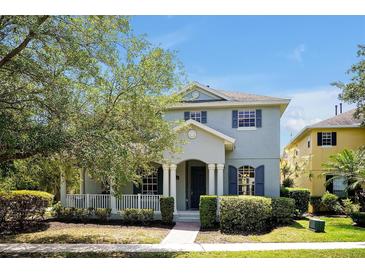 Charming two-story home featuring blue shutters, a covered porch, and well-maintained landscaping at 14522 Old Thicket Trace, Winter Garden, FL 34787