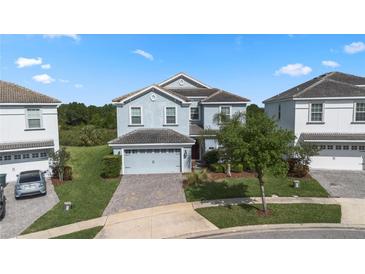 Charming two-story home with a two-car garage, lush landscaping, and a brick driveway at 1571 Palmero Way, Davenport, FL 33896