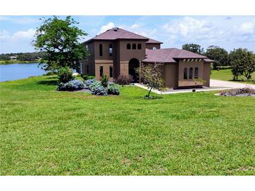 Stunning two-story home boasts a lake view, beautiful landscaping, and a well-manicured lawn at 36813 Barrington Dr, Eustis, FL 32736