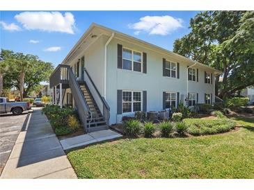 Two-story condo building with lush landscaping, gray shutters, stairway entry, and manicured lawn at 4870 Conway Rd # 106, Orlando, FL 32812