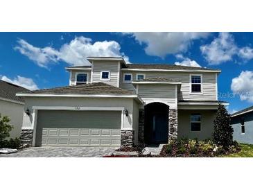 Two-story home featuring a two-car garage, stone accents and manicured landscaping at 523 Silver Palm Dr, Haines City, FL 33844